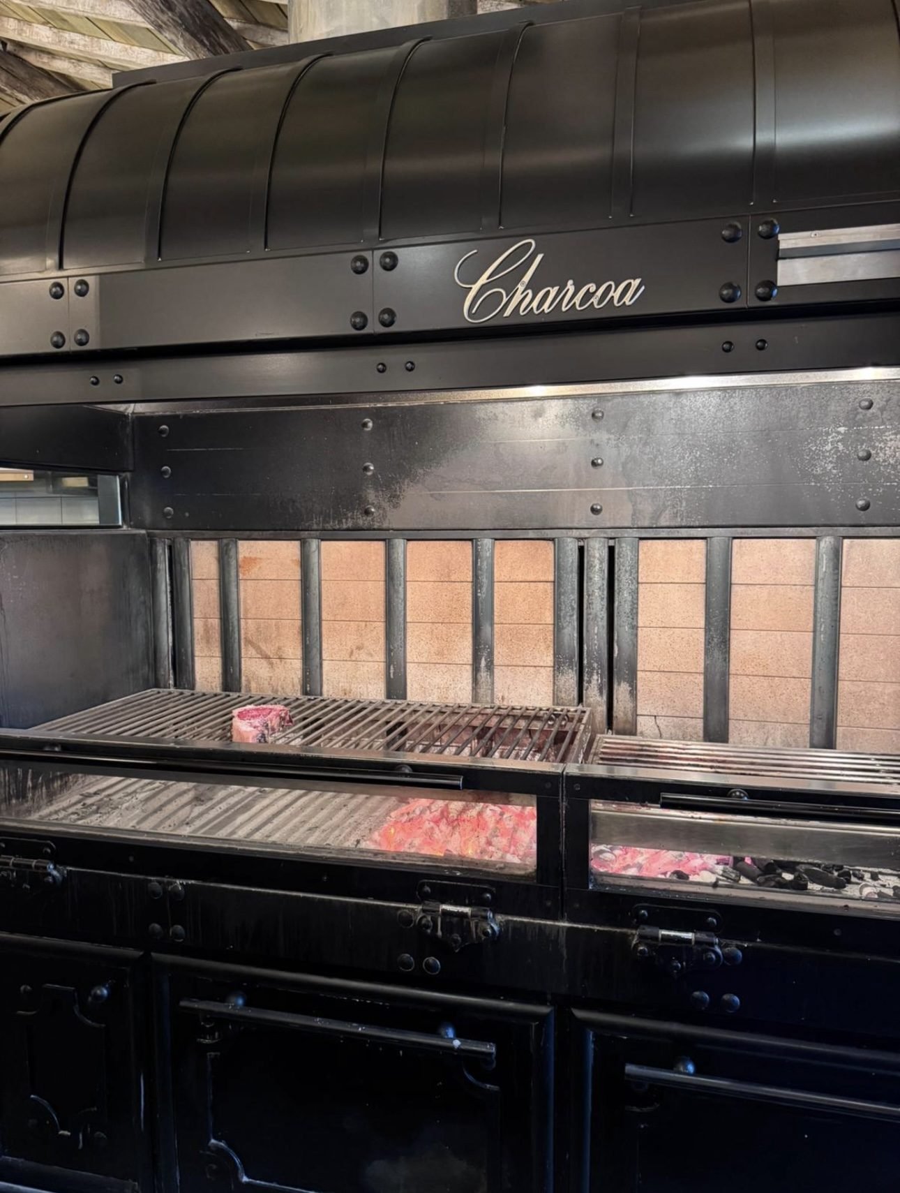 Closed charcoal grill with embers glowing behind the door