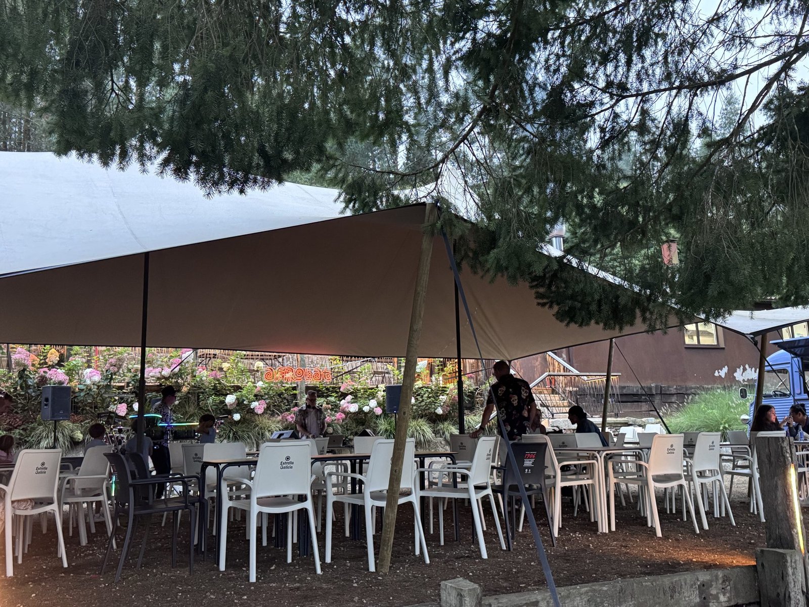 Carpa exterior con mesas corridas montadas entre los árboles