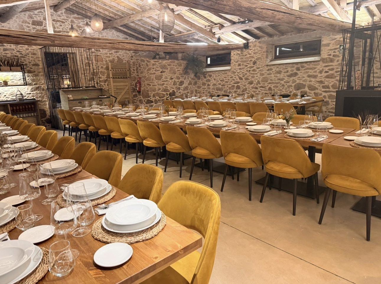 Salón de eventos con mesas largas montadas y sillas de terciopelo ámbar