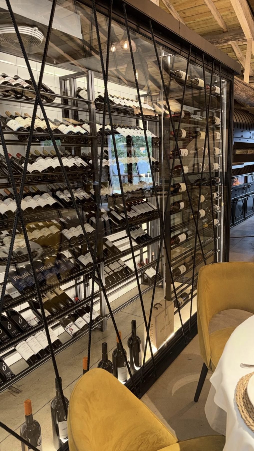 Pared de botellas de vino junto a las butacas de terciopelo ámbar