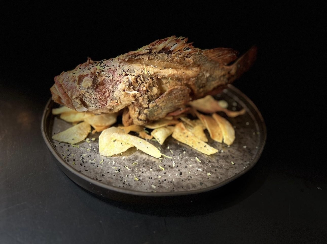 Whole grilled fish served over panadera potatoes